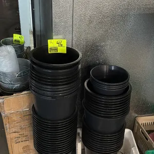 Quantity of assorted poly flowerpots. Includes two stacks of black plastic nursery pots in varying sizes, including 14" diameter pots. White plastic t