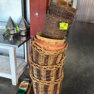Assorted display and produce baskets. Includes three tall round woven wicker baskets, two rectangular dark wicker baskets with handles, nested wooden 