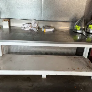 Stainless steel top work table. Features a painted wood base with a lower wooden shelf and an integrated stainless steel rear backsplash. 93"L x 30"W 
