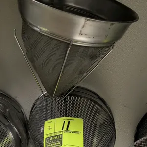 Assorted metal china cap strainers. Includes one fine mesh conical strainer with a wire support stand and one perforated metal conical strainer with a