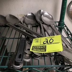 Assorted metal serving spoons. Includes 15 pieces of various styles such as solid, slotted, and perforated spoons. Features a mix of stainless steel c