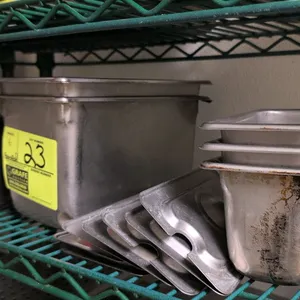 Assorted stainless steel kitchen insert pans and lids. Includes various deep food pans in multiple sizes along with corresponding stainless steel lids