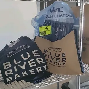 Blue River Bakery apparel and accessories lot. Includes navy blue short-sleeve t-shirt with printed logo, dark-colored pants in a protective plastic c