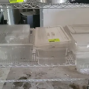 Assorted clear polycarbonate food pans. Includes various sizes of tubs, matching lids, and clear slotted drain shelf inserts. Wire shelving not includ
