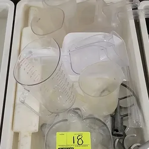 Assorted bakery smallwares with plastic tub. Includes (1) 2L clear plastic measuring pitcher, assorted frosted plastic measuring cups, (2) plastic sco