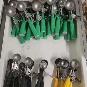 Lot of 35 assorted commercial portion control dishers. Features color-coded plastic handles with metal thumb-lever release mechanisms, including green