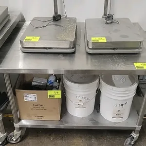Portable stainless steel work table. Features a stainless steel top and undershelf. Mounted on casters. Dimensions: 48" x 36" x 34". Scales and bottom