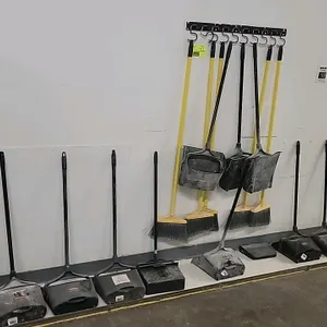 Assorted commercial lobby cleaning supply lot. Includes Rubbermaid upright lobby dustpans, yellow-handled lobby brooms, and (1) wall-mounted multi-hoo