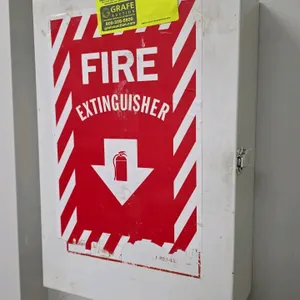 Metal first aid cabinet. Features white metal construction with a top carrying handle, three interior shelves, and plastic organizer pockets on the in