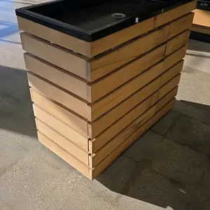 Bradley portable wood produce display. Features a natural wood slatted exterior and a black plastic top display tray with a center drain. Measures 36"