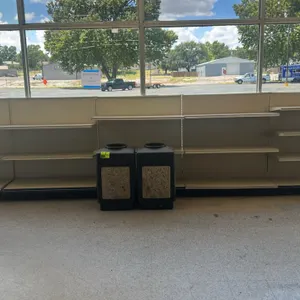 20'L of Lozier single-sided wall shelving. Features adjustable shelves and solid backing panels. Dimensions: 53"H with 19"D base shelves. Trash cans a