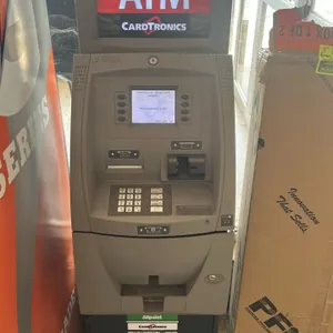 Triton ATM machine. Features Cardtronics topper, digital display, keypad interface, card reader, receipt printer, and cash dispenser. Mounted on a sec