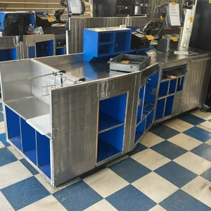 AFCO stainless steel checkout lane. Features stainless steel exterior panels with blue interior shelving and storage compartments. Includes integrated