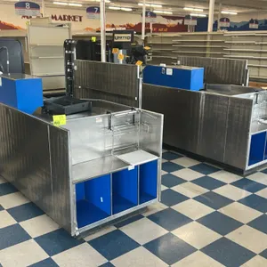 AFCO stainless steel checkout lane. Features a conveyor belt, integrated bagging section with wire bag rack, and blue laminate under-counter storage c