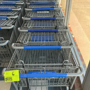 Metal wire shopping cart. Features a zinc-plated steel wire basket, blue plastic handle sleeve, and a folding child seat with a safety strap. Equipped