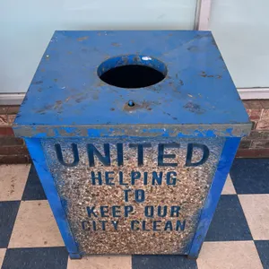 Wheeling-Pittsburgh stone panel trash receptacle. Features a blue-painted steel frame with stone aggregate side panels, a hinged lid with a circular o