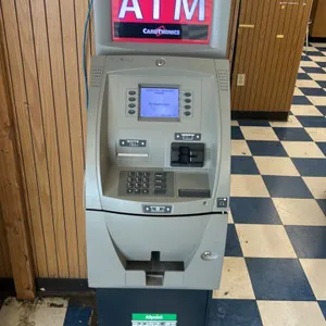 Triton ATM machine. Features Cardtronics topper, integrated display screen, physical keypad, card reader, and receipt printer. Mounted on a black pede