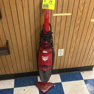 Dirt Devil Power Stick vacuum cleaner. Features a red lightweight body, bagless dirt cup, integrated hose, and attached power cord.