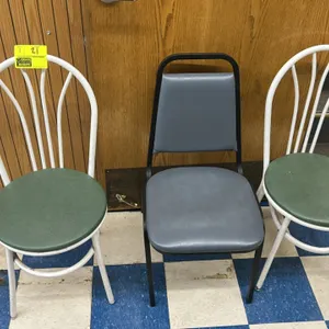 Assorted metal frame chairs. Includes (2) white metal chairs featuring green vinyl padded seats and arched spindle backs, and (1) black metal banquet-