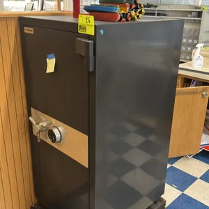 AMSEC metal office safe. Features an electronic digital keypad lock and a three-spoke handle. Includes combination code. 25"x29"x53". Mounted on a woo