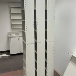 Assorted pharmacy shelving and built-ins. Includes multiple modular metal shelving bays, a laminate base cabinet with three doors, a wall-mounted uppe