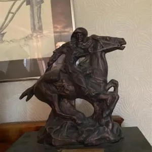 Cowboy riding horse statue on platform
