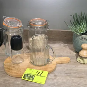 Assorted smallwares lot. Includes (2) glass storage jars with clamp lids, (1) ribbed glass pitcher, (1) spice grinder, (1) wooden cutting board, (1) w