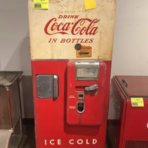 A Vintage Cavalier C-51 Coca-Cola Vending Machine. (Cavalier, 1950s) A classic bottle vending machine featuring a red and white steel cabinet with emb