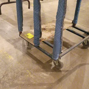 Steel rolling table transport cart. Features blue padded protective divider rails and a carpeted center base deck. Mounted on four swivel casters. Not