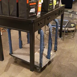 Wooden table with drawers. Features a black finish and drawers with metal pull handles. 60"x26"x31". Contents and furniture dolly are not included.