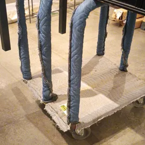 Rolling cart. Features a carpeted deck and four padded U-shaped upright support bars. Mounted on four swivel casters. Note: Quilted padding on upright