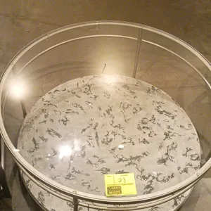 Round coffee table. Features a clear glass inset top, a gold-tone metal frame, and a lower shelf with a black and white faux marble patterned finish.