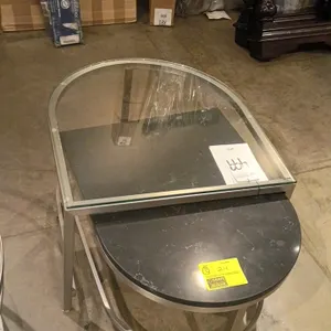 Modern nesting end table set. Features a two-piece design including an upper table with a clear glass top and a silver-tone metal frame, and a nesting