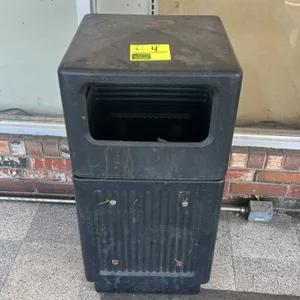 Poly trash bin. Features black molded plastic construction with side-access openings. Note: Lot includes two bins. One unit features an aggregate deco