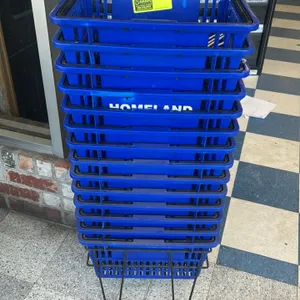 Lot of (12) blue poly shopping baskets with a metal floor stand. Baskets feature dual folding handles and white 'Homeland' branding on the sides. Set 