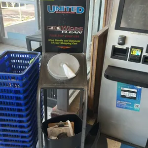 CartWipes sanitizing wipe stand. Features a metal frame construction, integrated top wipe dispenser with lid, and a branded sign board. Includes a mat