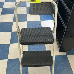 Cosco metal 2-step folding step stool. Features a white painted metal frame, two black textured steps, and an integrated high handrail for stability.