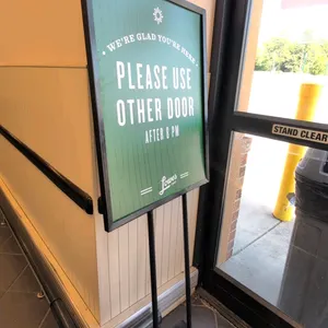 Metal sign stand. Features a black metal frame and flat rectangular base. Includes a double-sided green Lowes Foods sign insert reading 'Please Use Ot