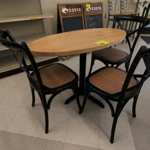 Dining table and chair set. Includes (1) oval wood-topped dining table and (3) black wood cross-back dining chairs with wicker seats. Table features a