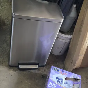 Tramontina 13-gallon step-on trash can. Features stainless steel construction with a hands-free foot pedal lid mechanism. Includes a box of Member's M