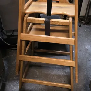 Tomlinson The Marston Chair wooden high chair. Features solid wood construction with a natural finish, stackable design, and a safety restraint strap 