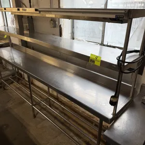 Stainless steel table with double-tier overshelf and integrated APW Wyott food warming strip heater. Features a 9'W x 18"D stainless steel top surface