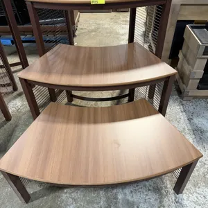 JSI 3-piece nested step-up display riser set. Features curved wood laminate tops with a woodgrain finish and brown metal wire grid bases. Designed for