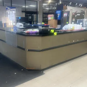 Laminate service counter. Features a wrap-around U-shaped design with a black countertop and gold-tone base. Equipped with integrated protective bumpe