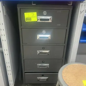 Metal 5-drawer vertical filing cabinet. Features a dark gray finish and recessed drawer pulls with integrated label slots. Scale, desk, stool, and oth