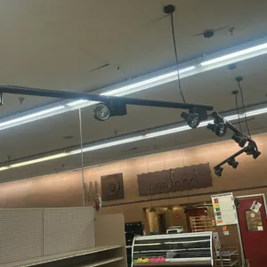Black track lighting system. Features multiple adjustable track light heads mounted on suspended black track rails. Ceiling-mounted design. Note: Buye