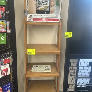 Wooden 4-tier merchandiser display shelf. Features four shelves and a top header board designed for promotional signage. Stationary floor-standing des
