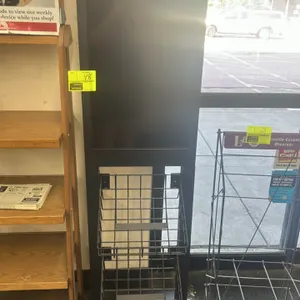 Digital sign stand. Features an integrated digital display screen housed in a black metal frame. Equipped with two wire merchandising baskets mounted 