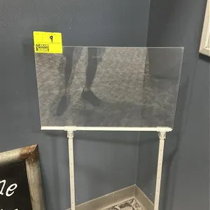 Adjustable metal sign stand. Features a clear acrylic sign holder clamped to a height-adjustable white metal frame with notched uprights. Mounted on a