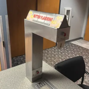 2012 Gold Medal 2396A counter butter dispenser system. Features stainless steel dispensing tower with lighted 'Butter Flavoring' sign, push-to-dispens
